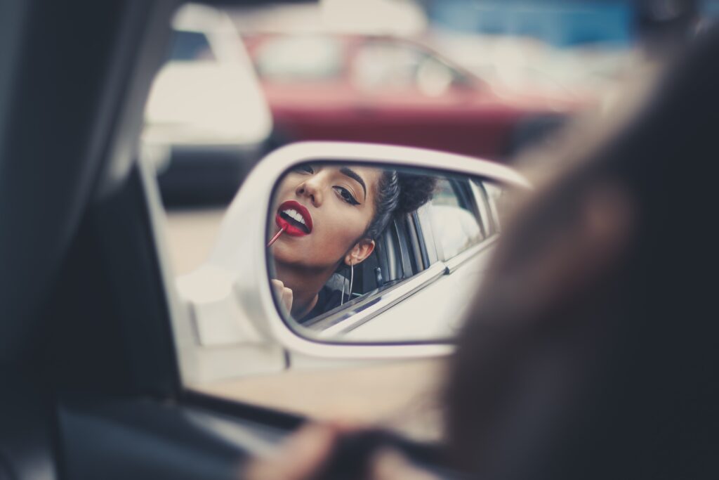 Woman applies lipstick in car